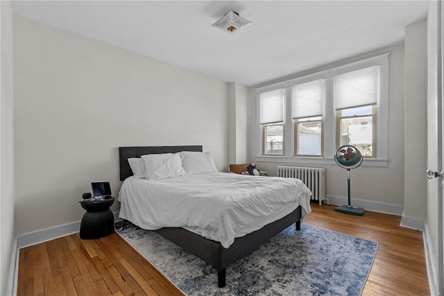 bedroom with radiator heating unit, baseboards, and wood-type flooring