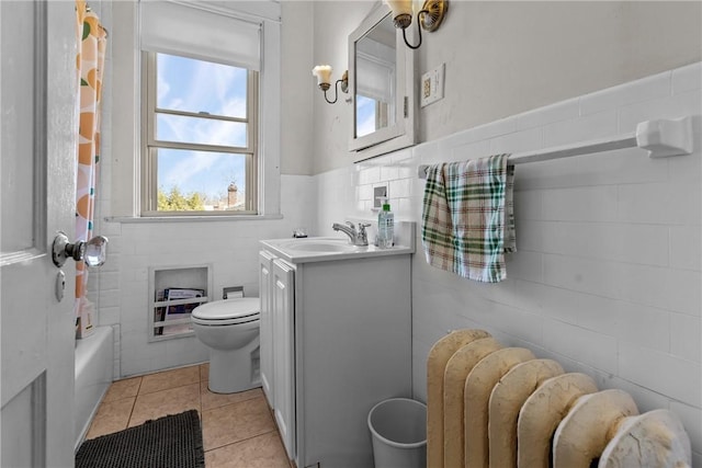 full bath with tile patterned flooring, a wainscoted wall, toilet, radiator heating unit, and vanity