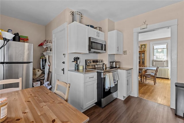 kitchen with tasteful backsplash, dark wood finished floors, white cabinetry, stainless steel appliances, and radiator