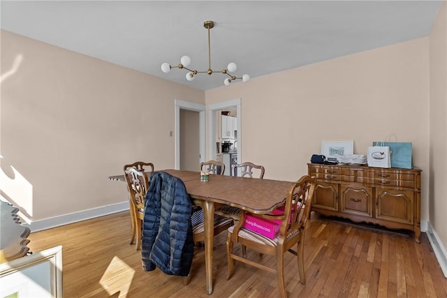 dining room featuring a chandelier, baseboards, and hardwood / wood-style flooring