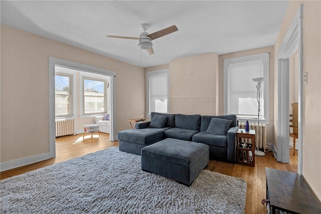 living area with radiator, wood finished floors, and baseboards