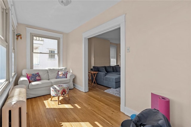 living room featuring light wood-style flooring, radiator heating unit, and baseboards