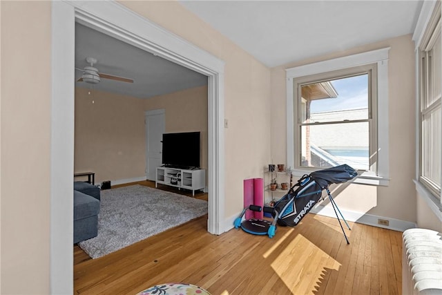 interior space featuring hardwood / wood-style floors, radiator heating unit, a ceiling fan, and baseboards