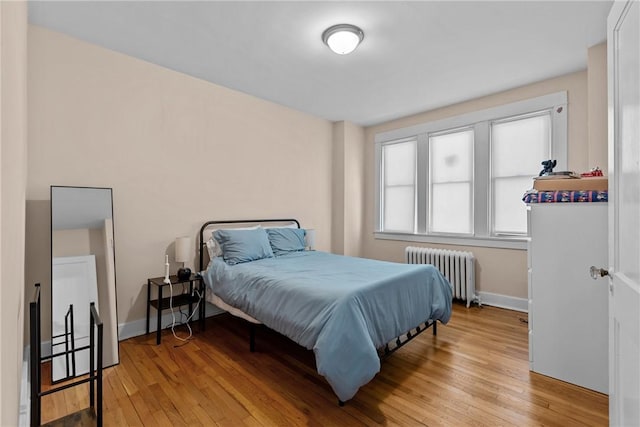 bedroom featuring light wood-style flooring, radiator, and baseboards