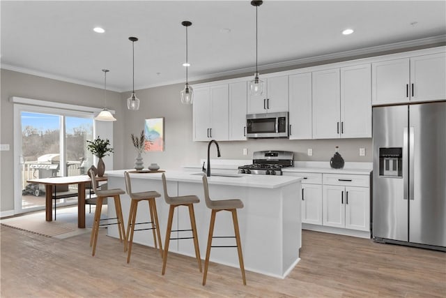 kitchen with a center island with sink, a sink, stainless steel appliances, light countertops, and crown molding