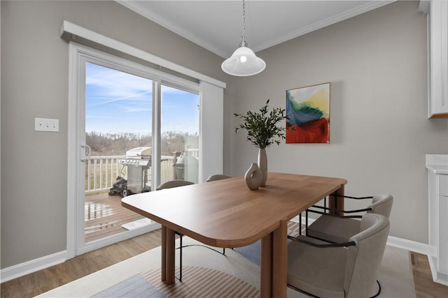 dining area featuring baseboards, light wood finished floors, and ornamental molding