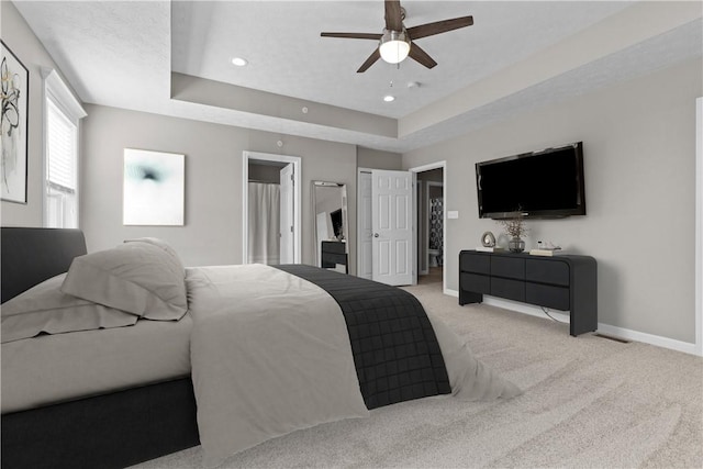 bedroom featuring recessed lighting, light colored carpet, baseboards, and a tray ceiling