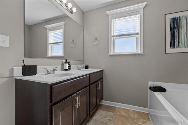 full bath with plenty of natural light, baseboards, and a sink