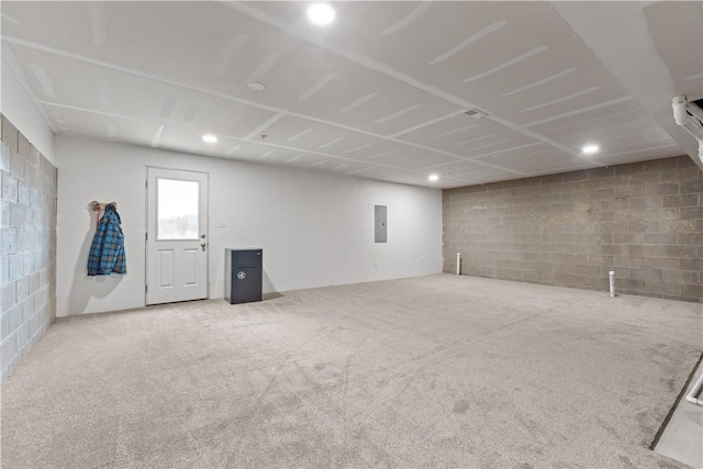 basement featuring concrete block wall, electric panel, and carpet floors