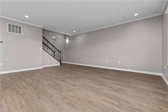 empty room with wood finished floors, visible vents, baseboards, stairs, and crown molding