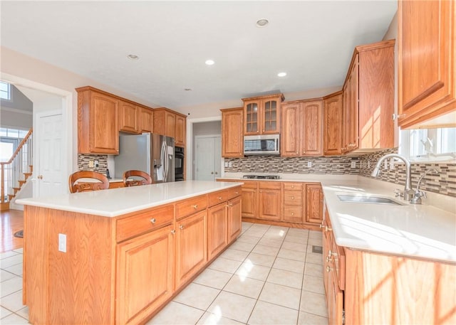 kitchen with a sink, a center island, appliances with stainless steel finishes, light countertops, and light tile patterned floors