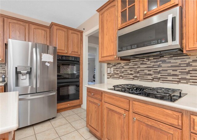 kitchen featuring glass insert cabinets, black appliances, light tile patterned flooring, and light countertops