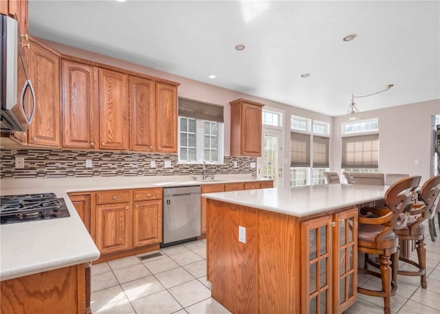 kitchen with tasteful backsplash, appliances with stainless steel finishes, a kitchen island, and light tile patterned flooring