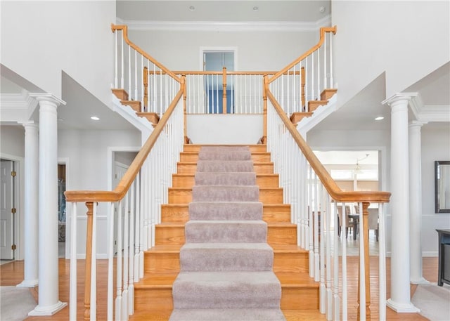 staircase featuring decorative columns, a towering ceiling, and ornamental molding