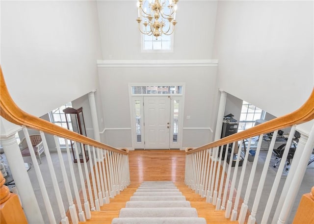 entrance foyer with a notable chandelier, stairs, a towering ceiling, and wood finished floors