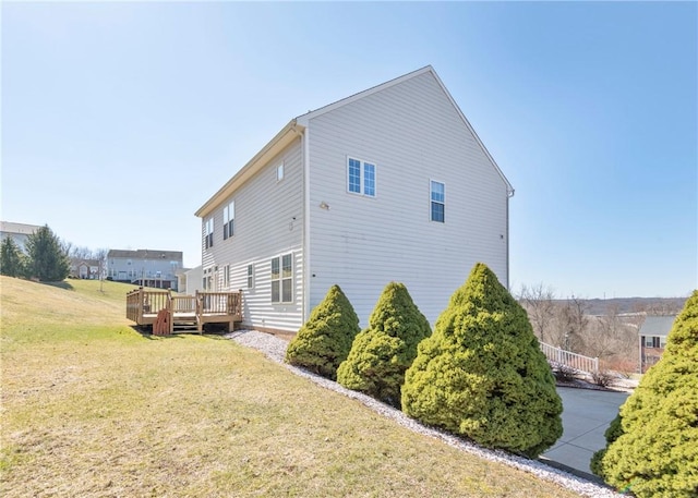 view of side of home featuring a lawn and a wooden deck