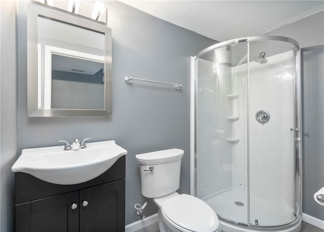 full bathroom featuring vanity, a shower stall, toilet, and baseboards