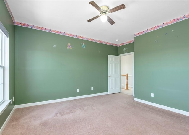 spare room featuring carpet, a ceiling fan, and baseboards