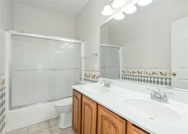 bathroom with a sink, toilet, double vanity, and tile patterned flooring