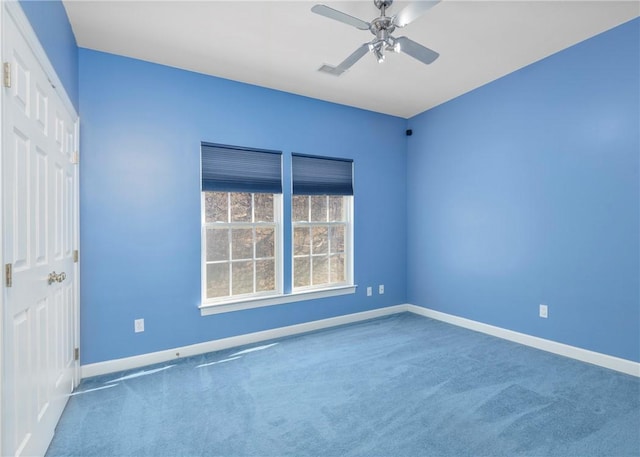 carpeted empty room featuring visible vents, a ceiling fan, and baseboards