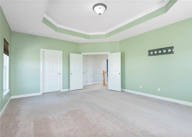 unfurnished bedroom with a tray ceiling, baseboards, and ornamental molding