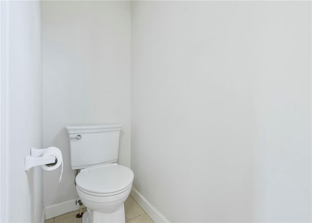 bathroom with baseboards, toilet, and tile patterned flooring