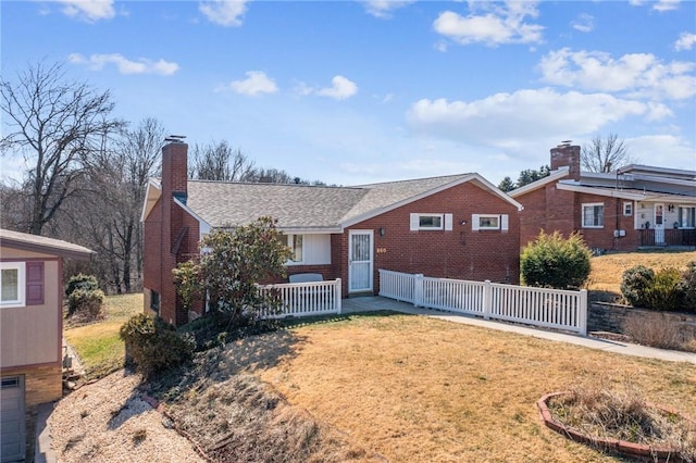 view of front of house featuring brick siding, a chimney, a front lawn, and fence