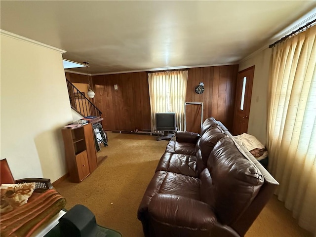 carpeted living room with stairs, wooden walls, and ornamental molding