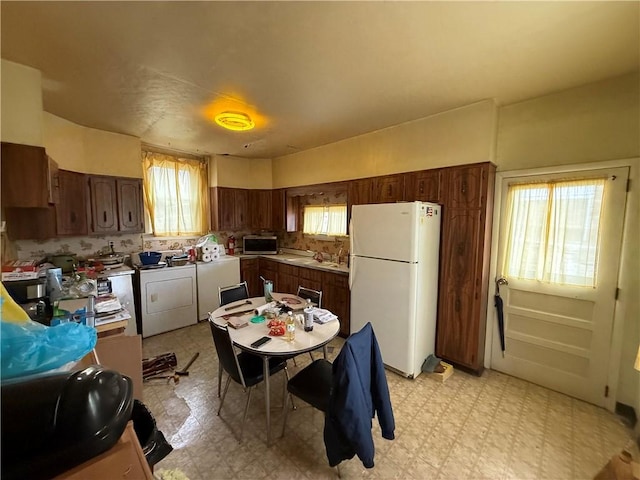 kitchen with stainless steel microwave, light floors, washer / clothes dryer, and freestanding refrigerator