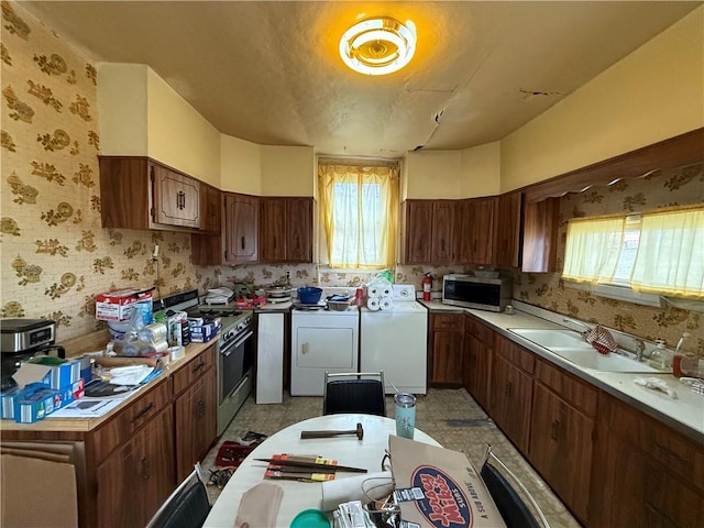 kitchen with stainless steel microwave, a healthy amount of sunlight, a sink, and gas range oven