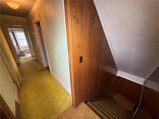 corridor with baseboards and light carpet