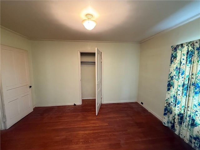 unfurnished bedroom featuring a closet, baseboards, wood finished floors, and ornamental molding