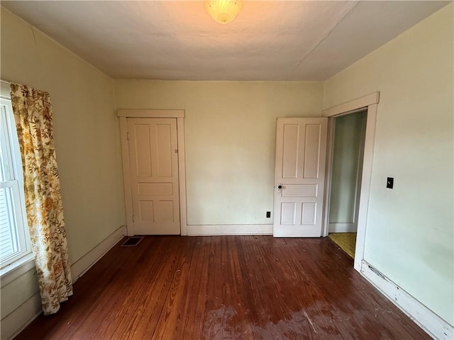 spare room featuring visible vents, a baseboard heating unit, baseboards, and wood finished floors