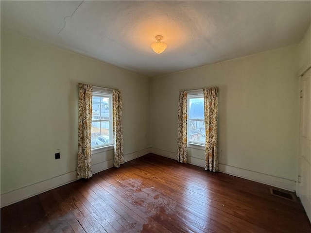 spare room with visible vents, a healthy amount of sunlight, and wood-type flooring