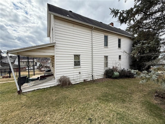 view of side of home with a chimney and a yard