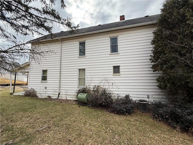 rear view of property with a yard, cooling unit, and a chimney