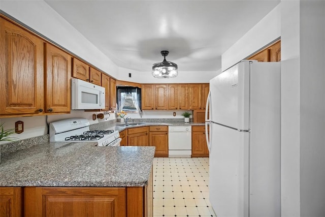 kitchen with light floors, brown cabinets, a peninsula, white appliances, and a sink