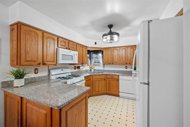 kitchen featuring light floors, a peninsula, brown cabinetry, white appliances, and a sink