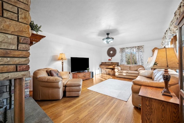 living room with wood-type flooring and a stone fireplace