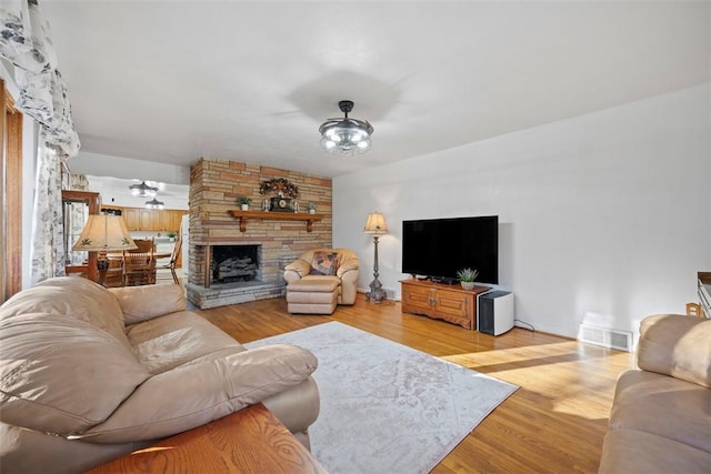 living room with light wood-type flooring, visible vents, and a fireplace