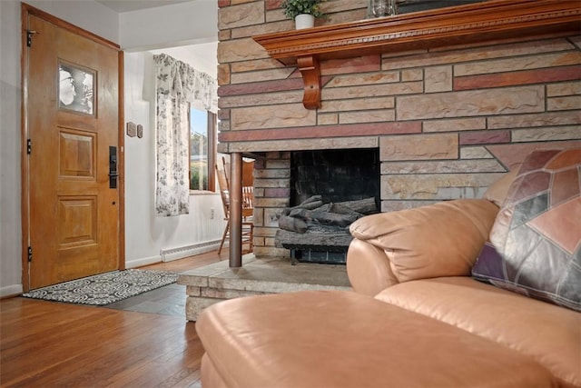 living area featuring a stone fireplace, a baseboard radiator, baseboards, and wood finished floors