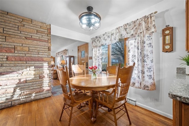 dining space featuring a baseboard heating unit, hardwood / wood-style flooring, and baseboards