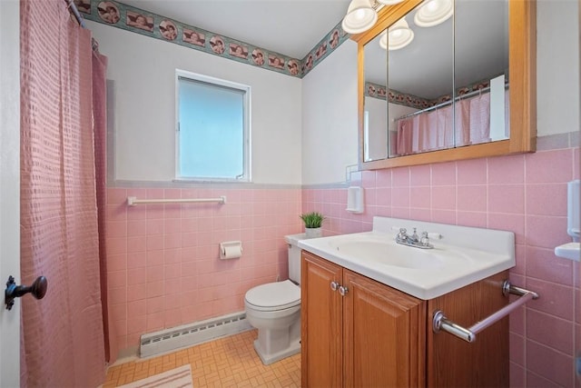 bathroom with toilet, a baseboard heating unit, tile walls, wainscoting, and vanity