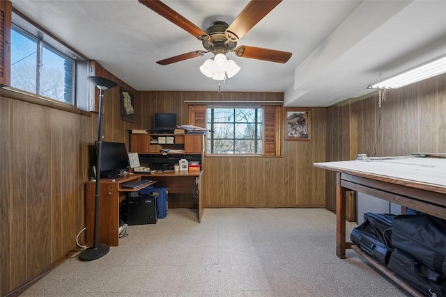 office area with light floors, ceiling fan, and wooden walls