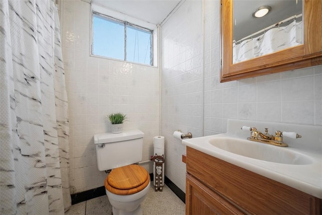 bathroom with toilet, curtained shower, tile walls, speckled floor, and vanity