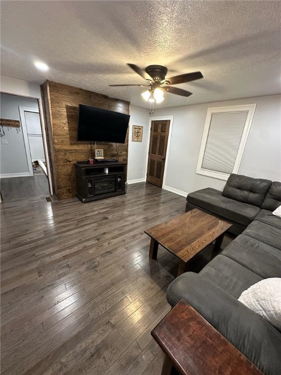 living area with a textured ceiling, baseboards, a ceiling fan, and hardwood / wood-style floors