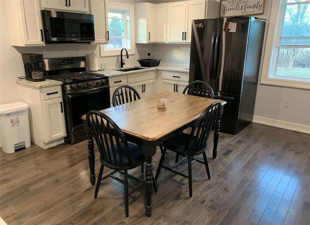 kitchen with gas stove, dark wood-style floors, white cabinets, and freestanding refrigerator