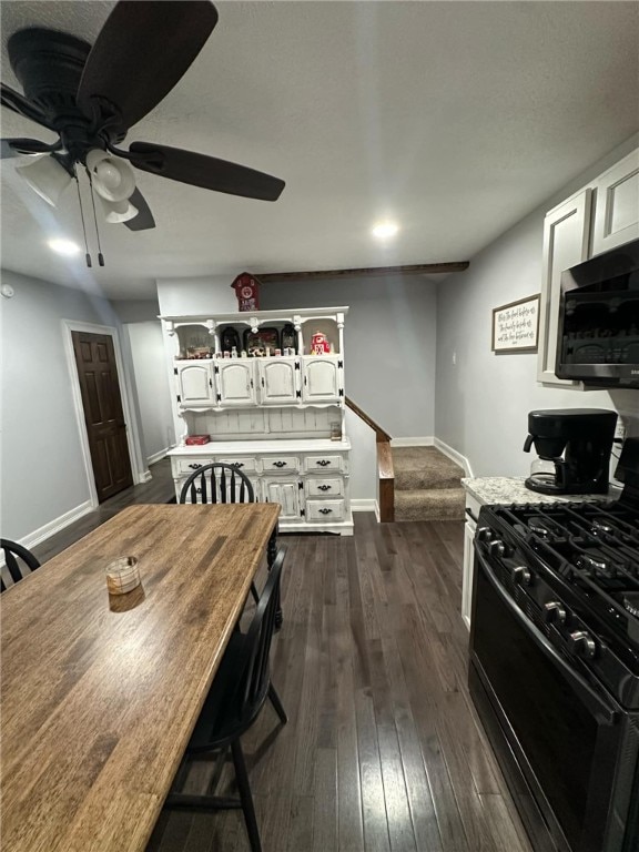 kitchen with dark wood-style floors, gas range, white cabinets, light countertops, and baseboards