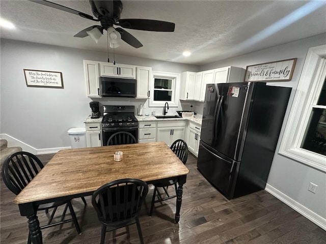 kitchen featuring black appliances, a sink, white cabinets, baseboards, and dark wood-style flooring