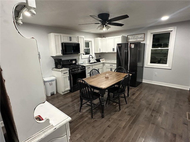 kitchen featuring black appliances, dark wood-style floors, light countertops, and a sink